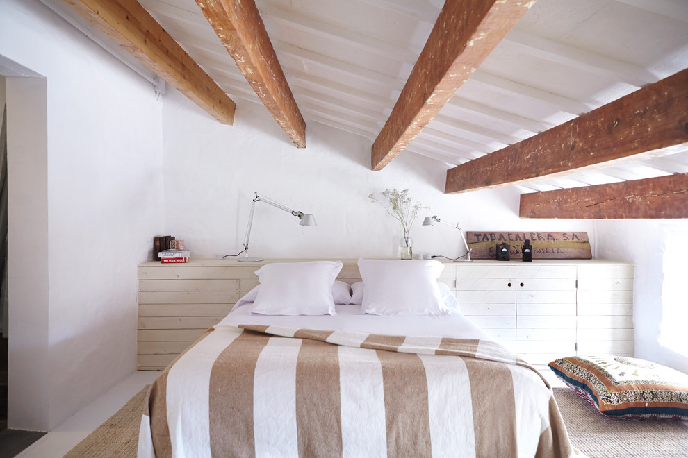 Modelo de dormitorio mediterráneo grande con paredes blancas, suelo de madera pintada, suelo blanco y techo inclinado