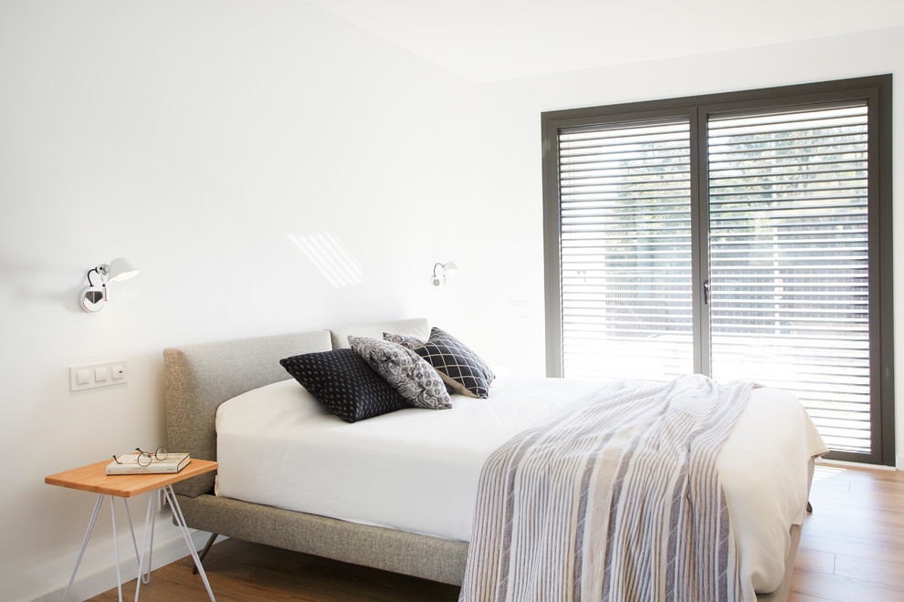 На фото: гостевая спальня (комната для гостей) в стиле модернизм с белыми стенами, паркетным полом среднего тона и бежевым полом с
