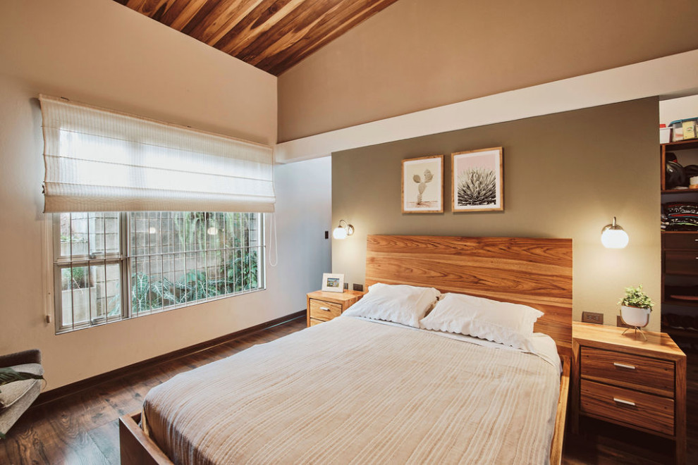 Cette photo montre une petite chambre parentale tendance avec un mur beige, sol en stratifié, aucune cheminée, un sol marron et un plafond en lambris de bois.