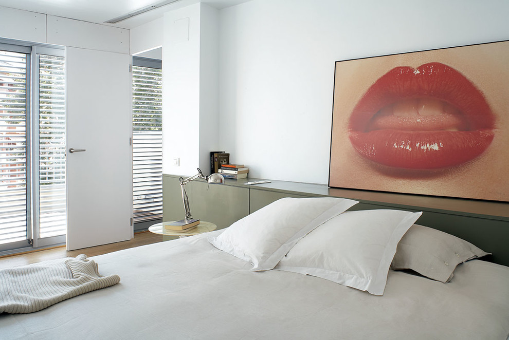 This is an example of a medium sized contemporary master bedroom in Barcelona with white walls, light hardwood flooring and no fireplace.