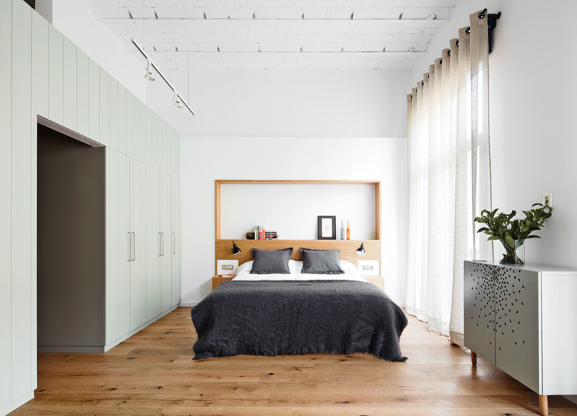 Ejemplo de dormitorio principal escandinavo grande sin chimenea con paredes blancas y suelo de madera en tonos medios