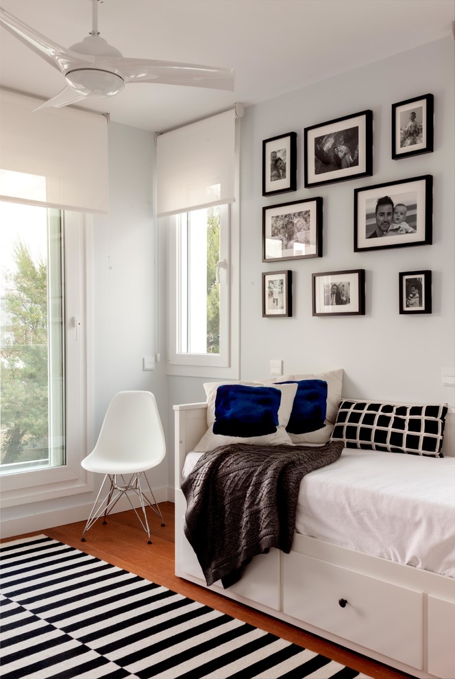 Idée de décoration pour une petite chambre d'amis minimaliste avec un mur blanc, un sol en bois brun et un sol marron.