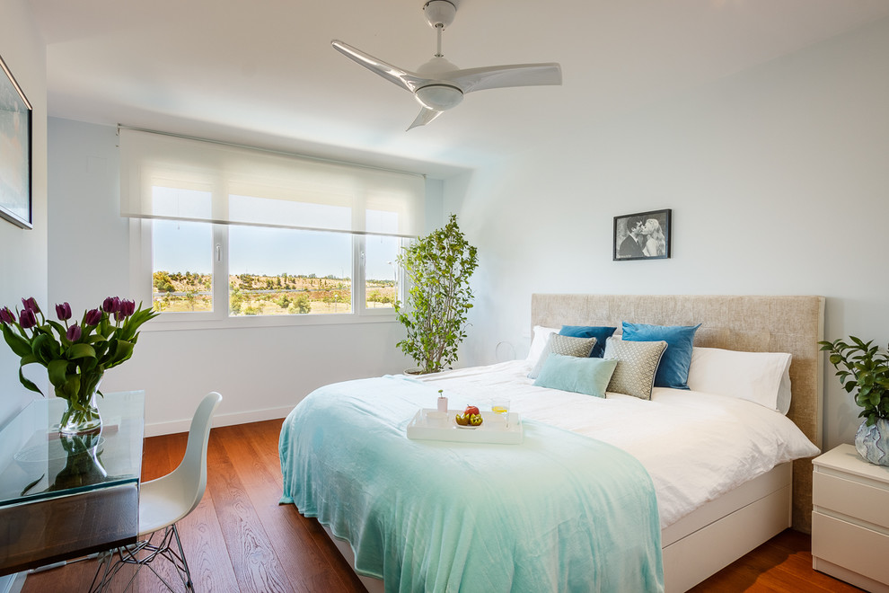 Diseño de dormitorio principal moderno de tamaño medio con paredes azules, suelo de madera en tonos medios y suelo marrón