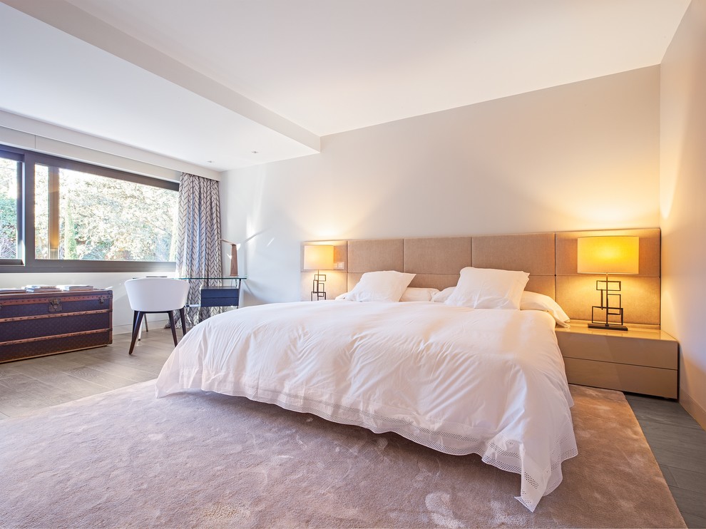 Großes Modernes Hauptschlafzimmer ohne Kamin mit weißer Wandfarbe und hellem Holzboden in Madrid