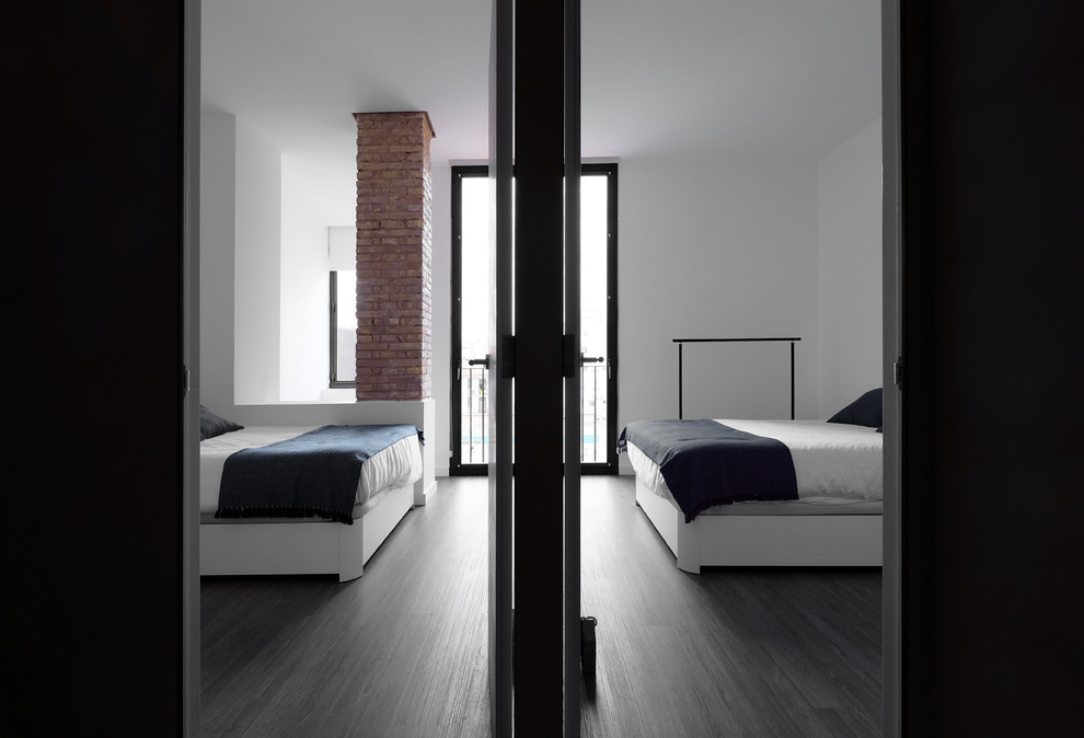 Imagen de dormitorio principal urbano de tamaño medio con paredes blancas, suelo laminado y suelo marrón