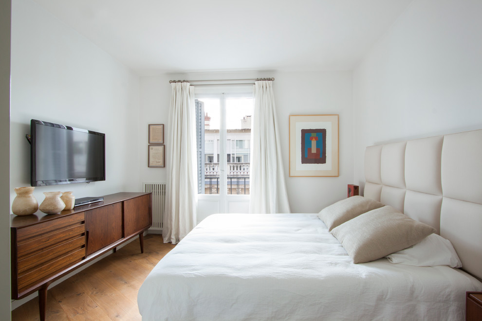 Imagen de dormitorio principal tradicional renovado de tamaño medio sin chimenea con paredes blancas y suelo de madera en tonos medios