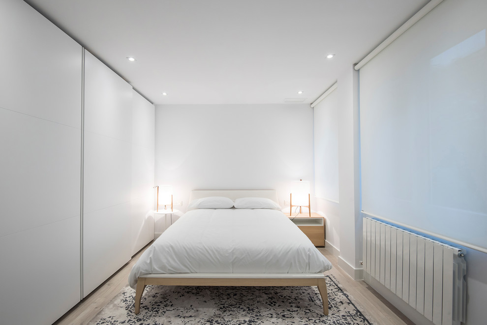 Foto de dormitorio principal escandinavo de tamaño medio con paredes blancas, suelo de madera clara y suelo beige