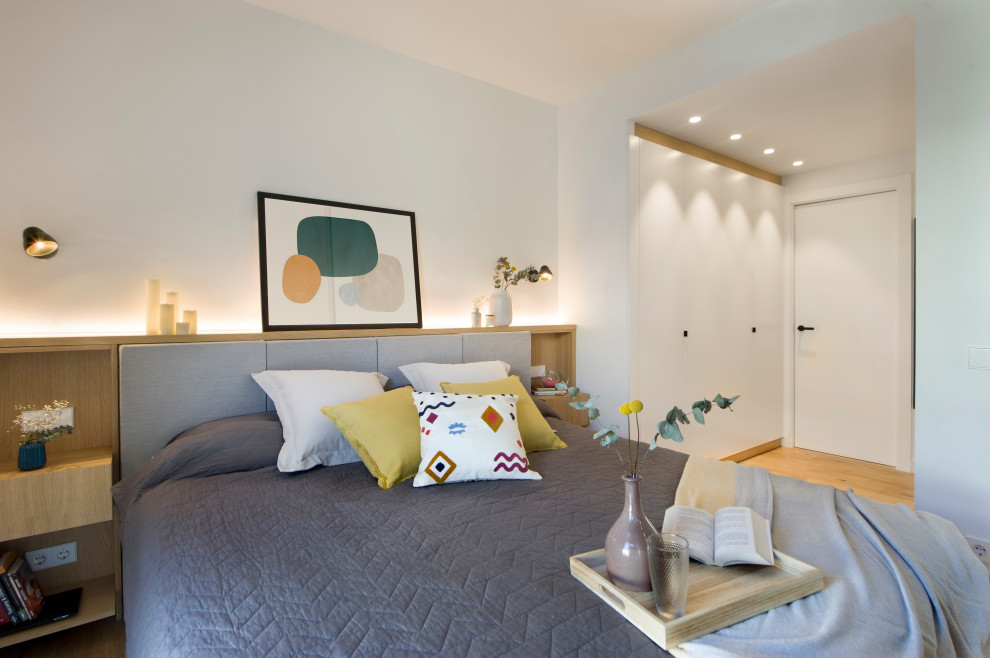 Idée de décoration pour une chambre design avec un mur blanc, un sol en bois brun et un sol marron.