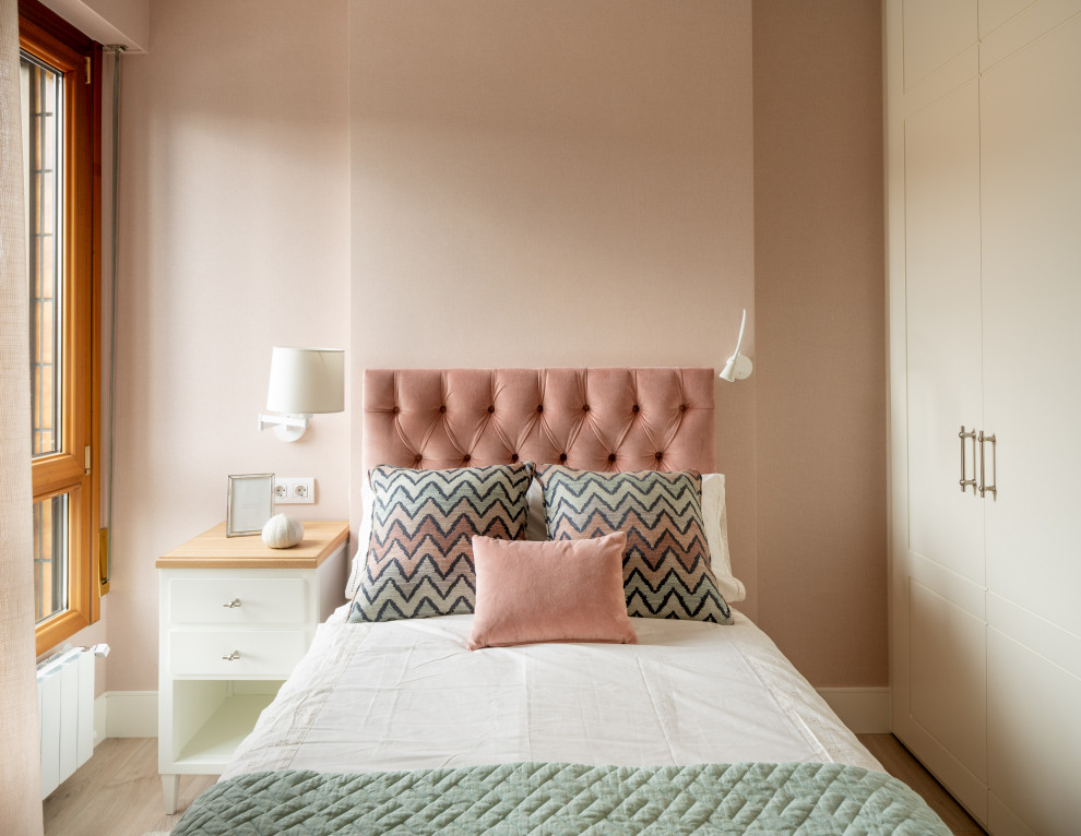 На фото: маленькая гостевая спальня (комната для гостей) в стиле неоклассика (современная классика) с розовыми стенами, полом из ламината, коричневым полом, многоуровневым потолком и обоями на стенах без камина для на участке и в саду