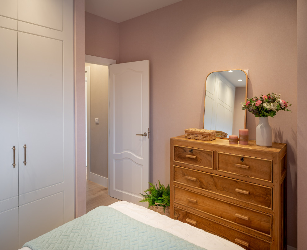 Идея дизайна: маленькая гостевая спальня (комната для гостей) в стиле неоклассика (современная классика) с розовыми стенами, полом из ламината, коричневым полом, многоуровневым потолком и обоями на стенах без камина для на участке и в саду
