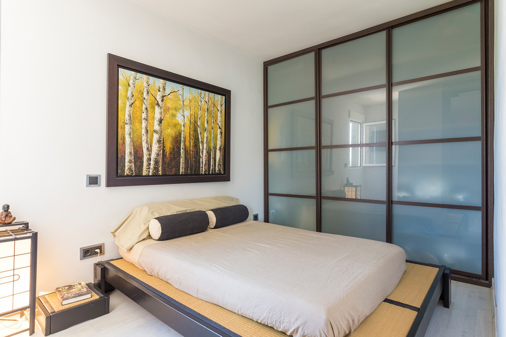Imagen de dormitorio principal de estilo zen de tamaño medio sin chimenea con paredes blancas y suelo de madera clara