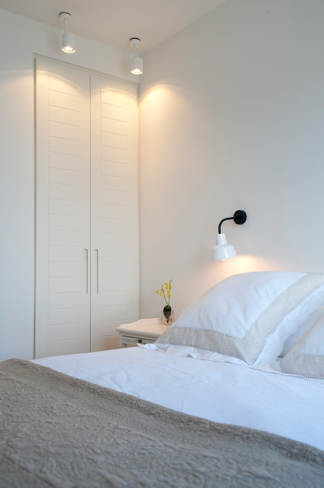 На фото: гостевая спальня среднего размера, (комната для гостей) в скандинавском стиле с белыми стенами, полом из ламината и коричневым полом с