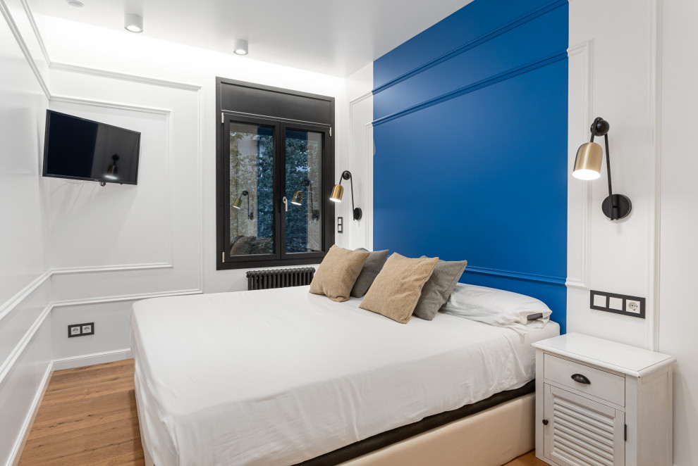 Kleines Klassisches Hauptschlafzimmer mit blauer Wandfarbe, braunem Holzboden, eingelassener Decke und vertäfelten Wänden in Barcelona