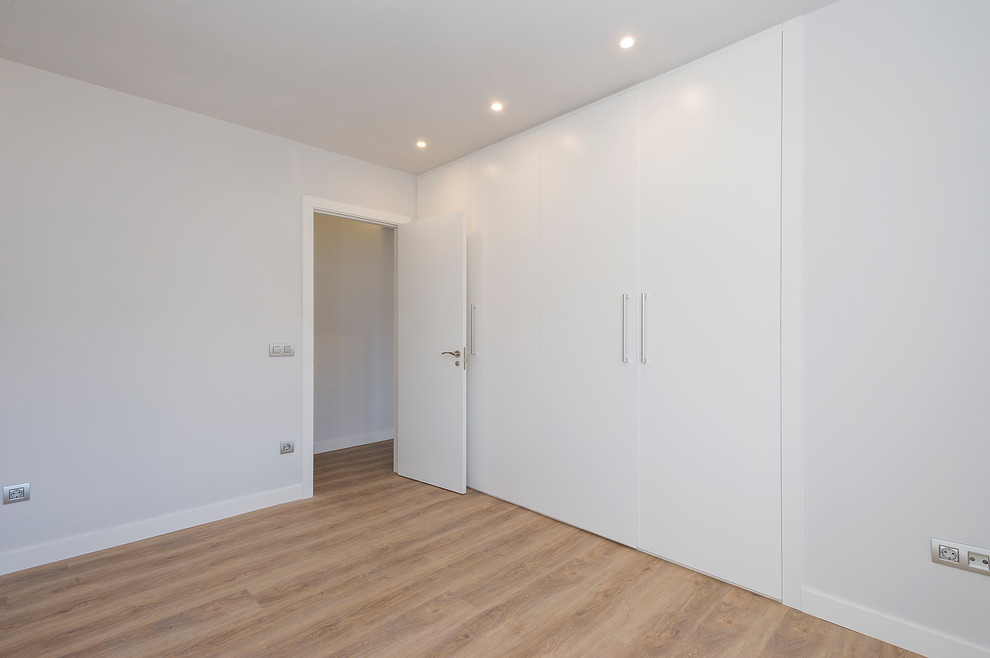 Diseño de habitación de invitados contemporánea de tamaño medio con paredes blancas, suelo de madera en tonos medios y suelo marrón