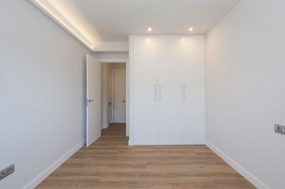 Mittelgroßes Modernes Gästezimmer mit weißer Wandfarbe, braunem Holzboden und braunem Boden in Madrid