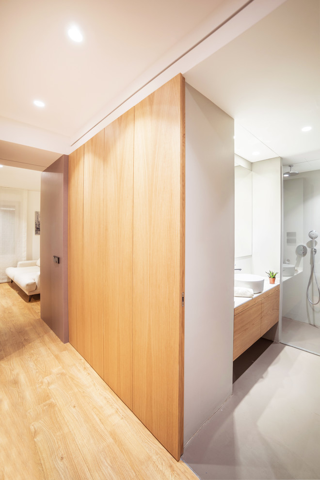 Imagen de dormitorio principal moderno de tamaño medio con paredes blancas, suelo de madera en tonos medios y suelo marrón