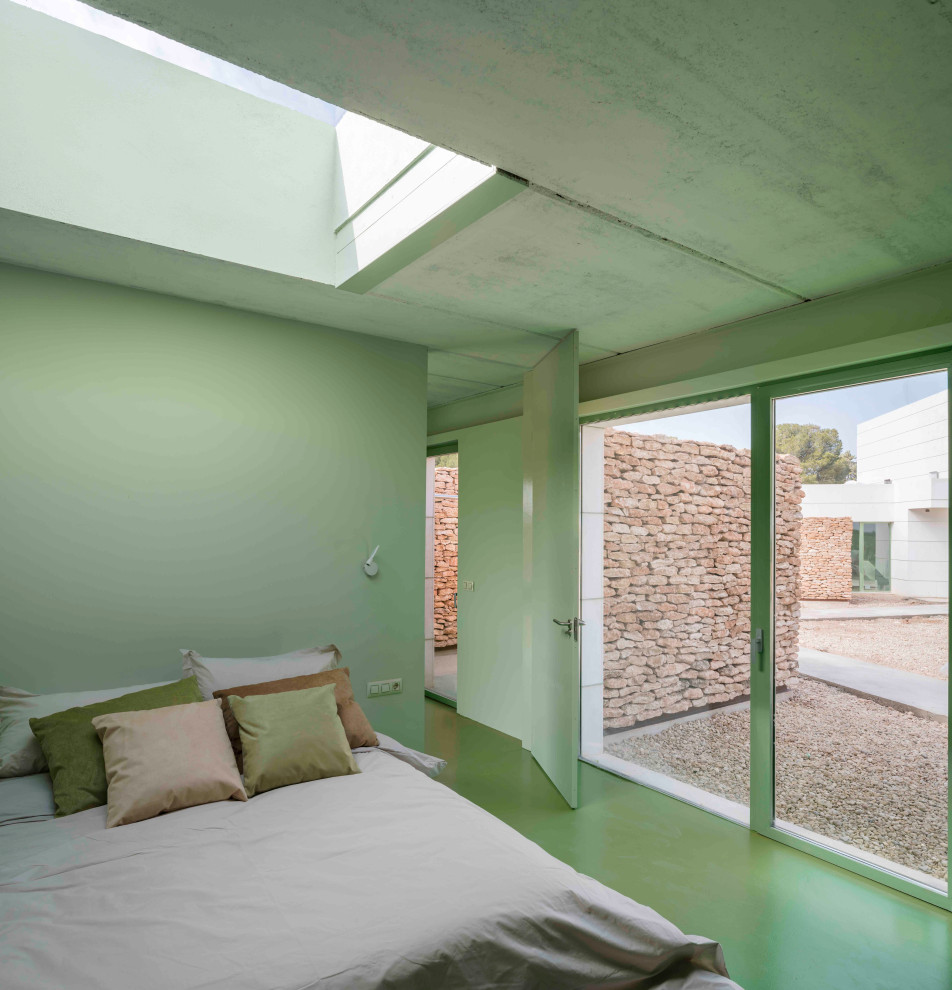 Inredning av ett modernt stort huvudsovrum, med gröna väggar, betonggolv och grönt golv