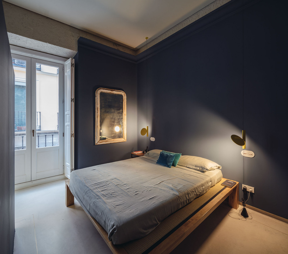 This is an example of a contemporary master bedroom in Madrid with blue walls, concrete flooring and blue floors.