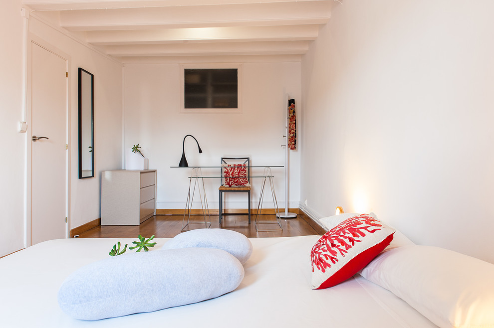 Medium sized world-inspired master bedroom in Barcelona with white walls and medium hardwood flooring.
