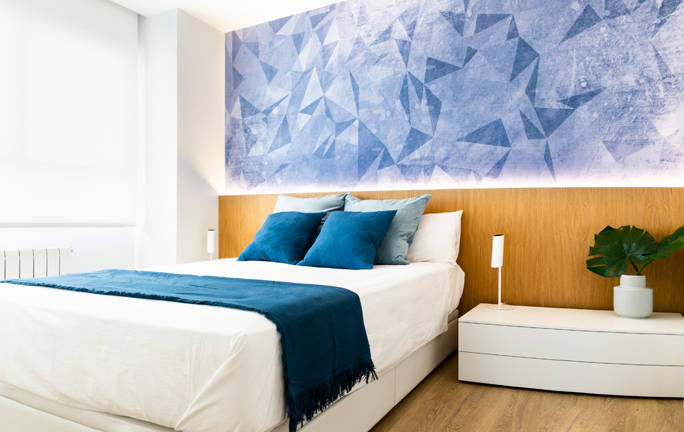 Foto di una camera matrimoniale design con pareti blu e pavimento in legno massello medio