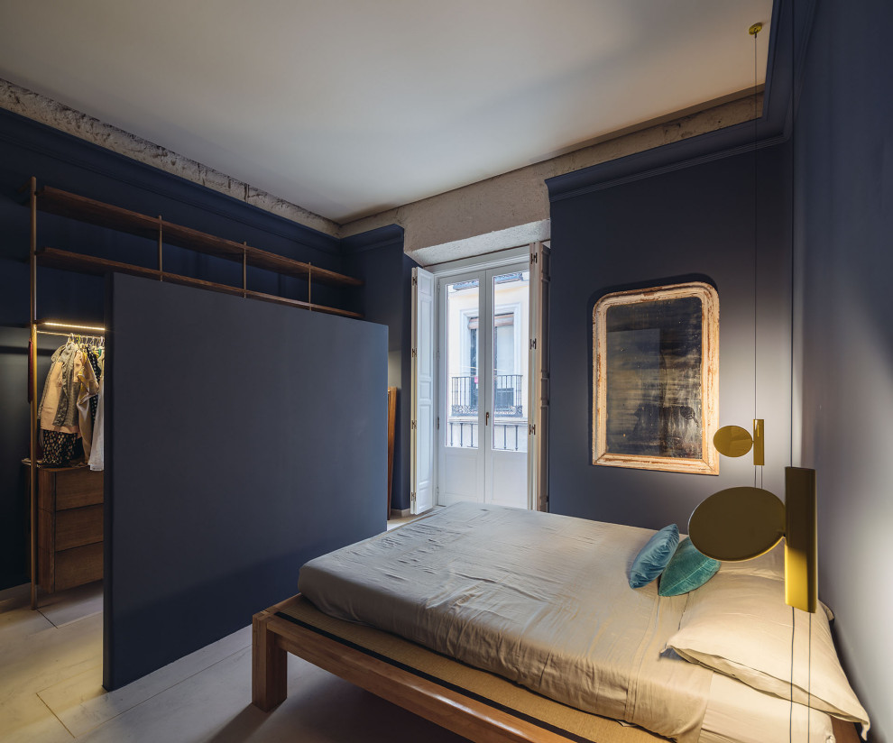 Imagen de dormitorio principal actual con paredes azules, suelo de cemento y suelo beige