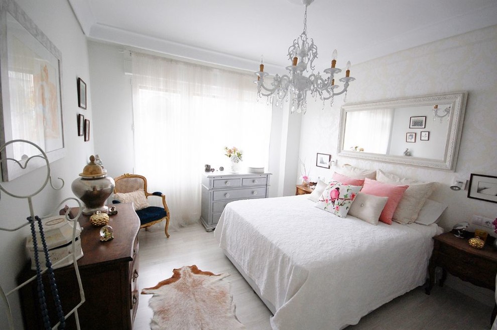 Modelo de dormitorio principal clásico renovado de tamaño medio con paredes blancas, suelo de madera clara y suelo gris