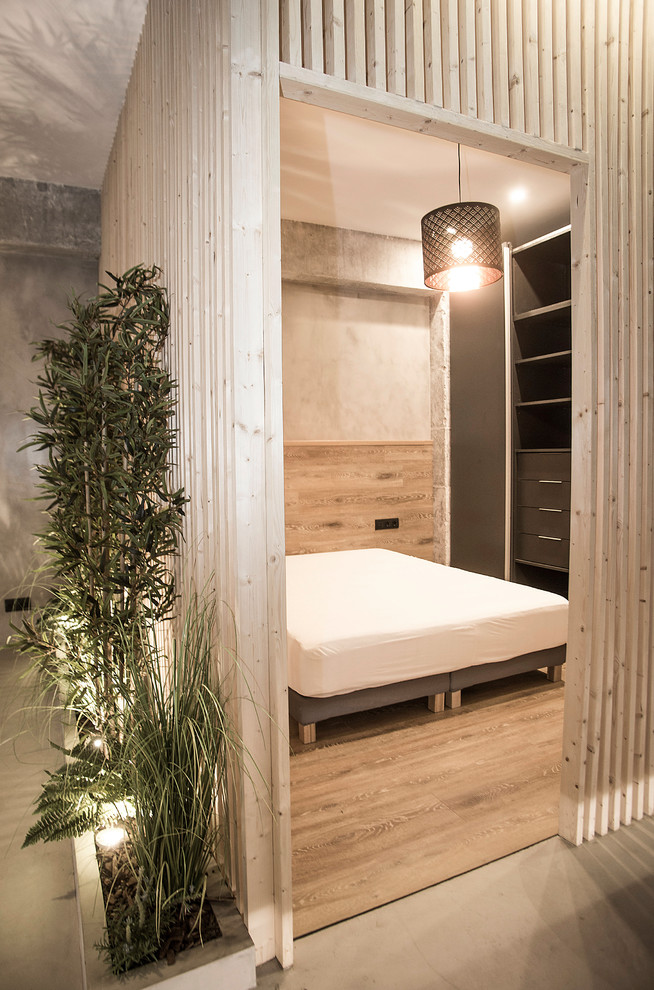 Immagine di una piccola camera da letto stile loft industriale con pareti grigie, pavimento grigio e pavimento in cemento