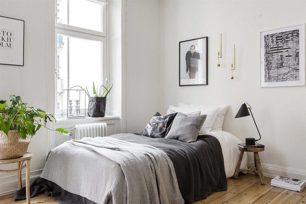 Mittelgroßes Skandinavisches Hauptschlafzimmer ohne Kamin mit weißer Wandfarbe, braunem Holzboden und braunem Boden in Sonstige