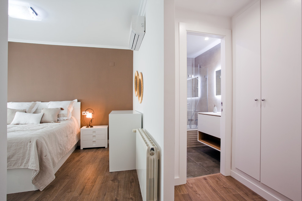 Ejemplo de habitación de invitados de tamaño medio con paredes blancas, suelo laminado y suelo marrón