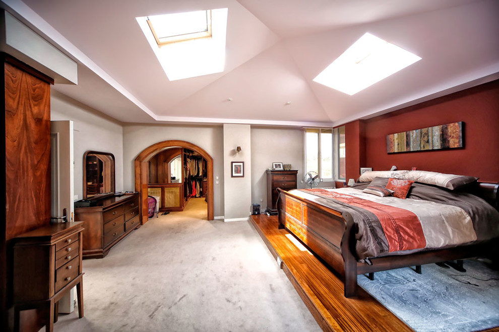 Modelo de dormitorio principal clásico grande sin chimenea con paredes multicolor y suelo de madera oscura