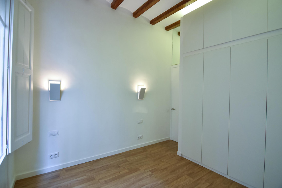 Aménagement d'une chambre parentale contemporaine de taille moyenne avec un mur blanc et un sol en bois brun.