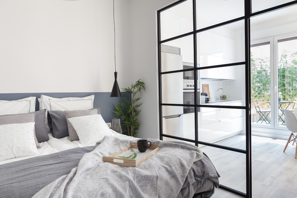 Modelo de dormitorio principal nórdico de tamaño medio con paredes blancas, suelo laminado y suelo gris