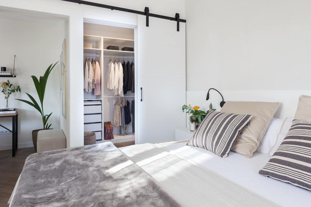 Mittelgroßes Skandinavisches Hauptschlafzimmer ohne Kamin mit weißer Wandfarbe, Laminat und braunem Boden in Madrid
