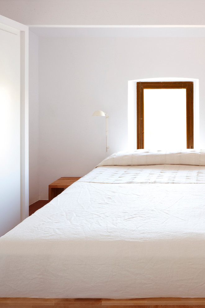Imagen de dormitorio principal mediterráneo de tamaño medio con paredes blancas, suelo de baldosas de cerámica y suelo marrón