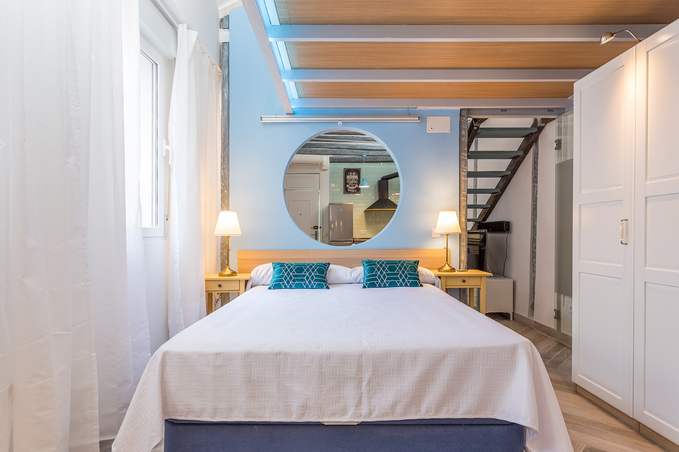Imagen de dormitorio principal actual de tamaño medio sin chimenea con paredes azules y suelo de madera en tonos medios