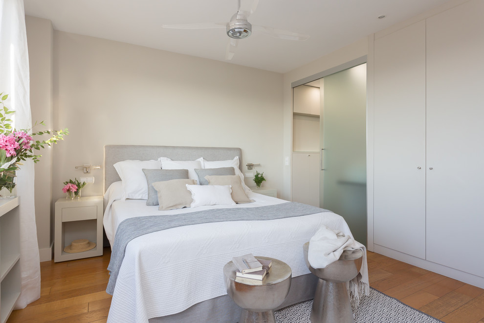 Maritimes Hauptschlafzimmer ohne Kamin mit beiger Wandfarbe und braunem Holzboden in Madrid