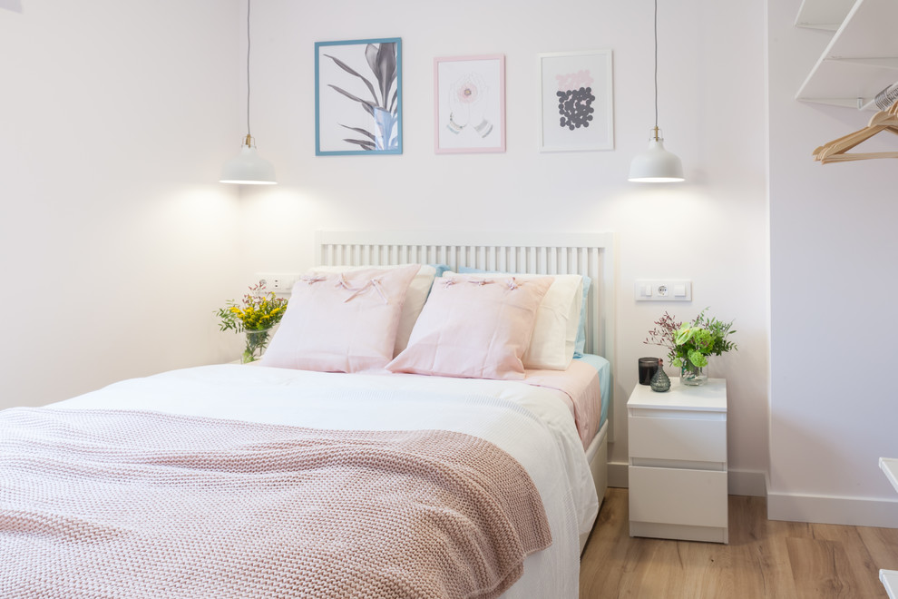 Ejemplo de dormitorio principal escandinavo pequeño con paredes blancas, suelo laminado y suelo marrón