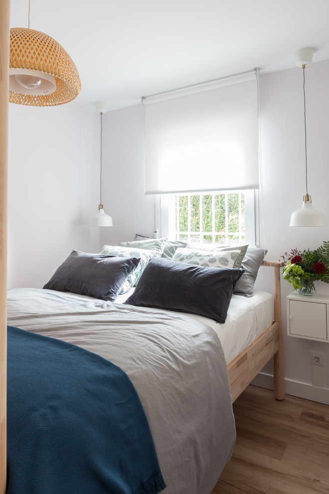 Kleines Skandinavisches Schlafzimmer im Loft-Style mit weißer Wandfarbe, Laminat und braunem Boden in Madrid