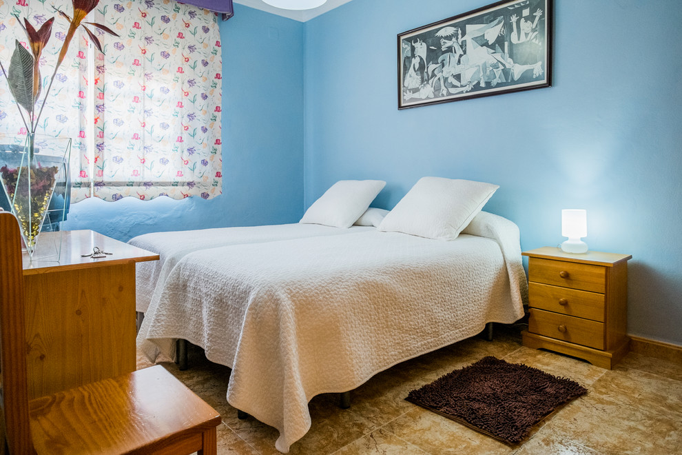 Ejemplo de habitación de invitados tradicional renovada de tamaño medio sin chimenea con paredes azules y suelo de travertino