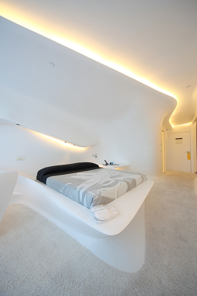Large contemporary master bedroom in Madrid with white walls, carpet and no fireplace.