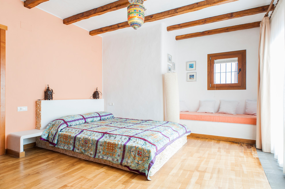 Diseño de habitación de invitados mediterránea con paredes blancas, suelo de madera clara y suelo beige
