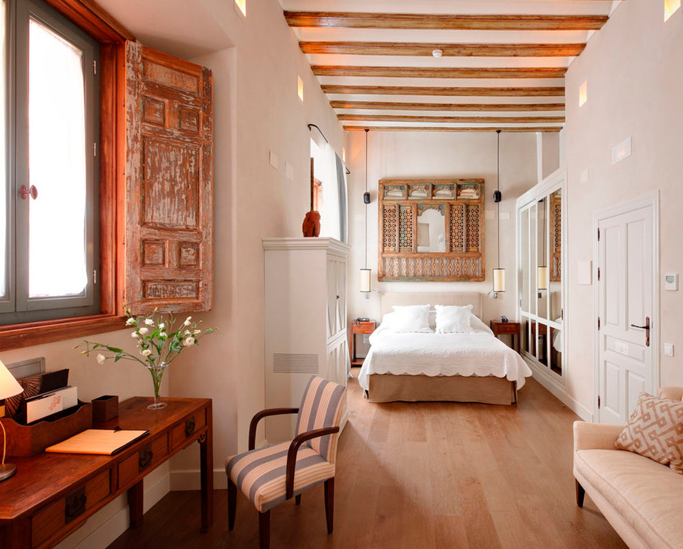 Photo of a large world-inspired master bedroom in Barcelona with white walls, light hardwood flooring and no fireplace.