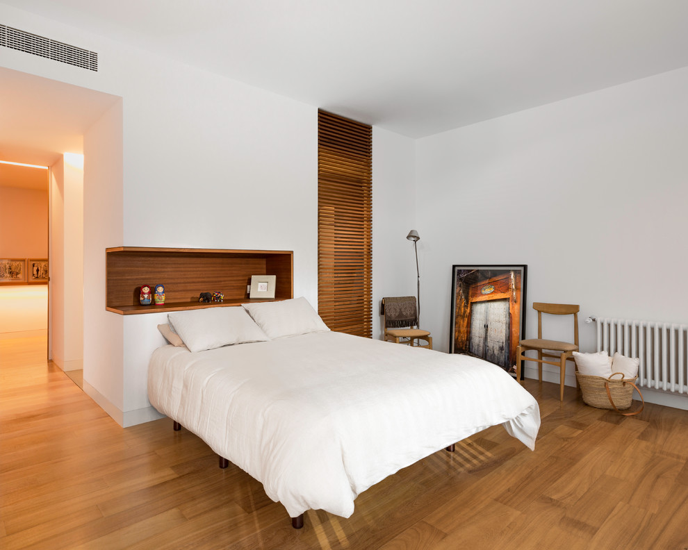 Foto di una grande camera degli ospiti minimalista con pareti bianche, pavimento in legno massello medio e nessun camino