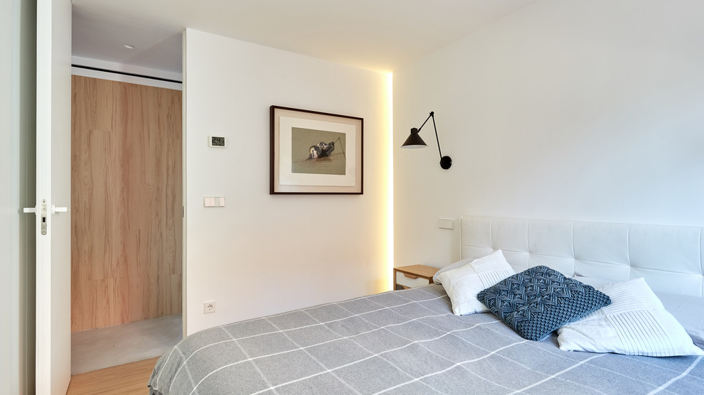 Mittelgroßes Nordisches Hauptschlafzimmer ohne Kamin mit weißer Wandfarbe, hellem Holzboden und braunem Boden in Madrid