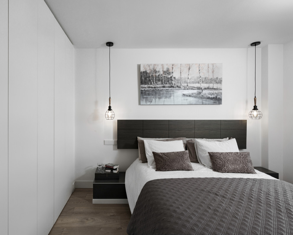 Ejemplo de dormitorio principal moderno de tamaño medio sin chimenea con paredes blancas, suelo de madera en tonos medios y suelo marrón