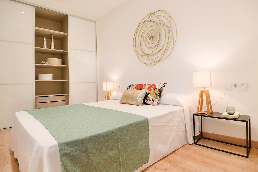 Cette image montre une chambre parentale design de taille moyenne avec un mur blanc, un sol beige et parquet clair.
