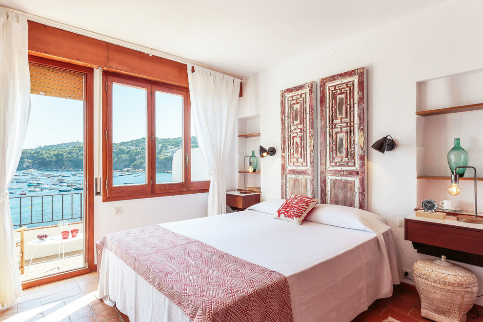 На фото: хозяйская спальня среднего размера в морском стиле с белыми стенами, красным полом и кирпичным полом без камина