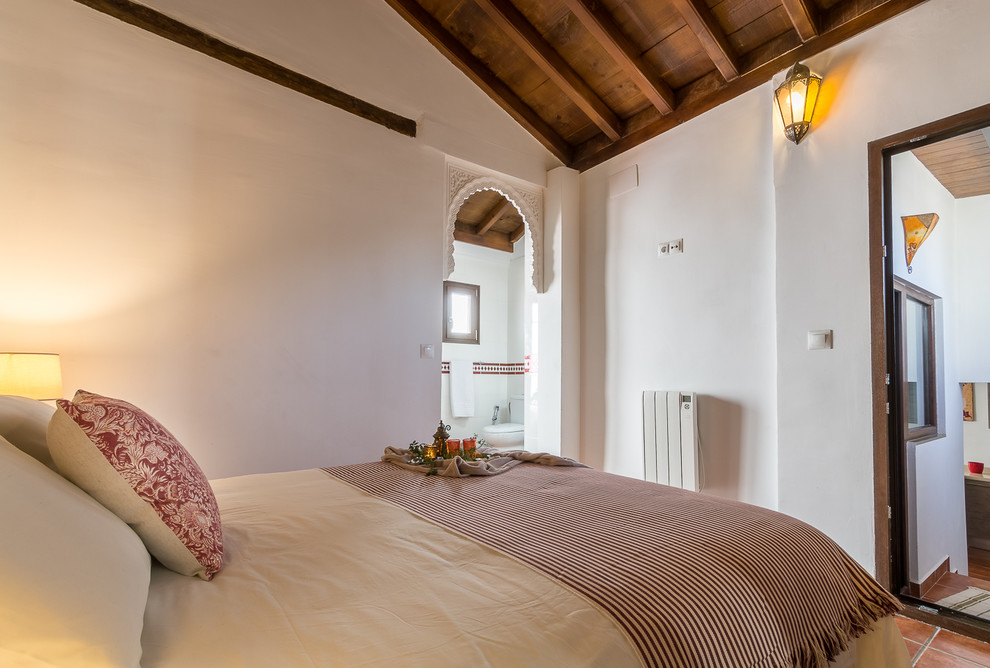 Esempio di una piccola camera degli ospiti stile shabby con pareti bianche, pavimento in terracotta e pavimento marrone