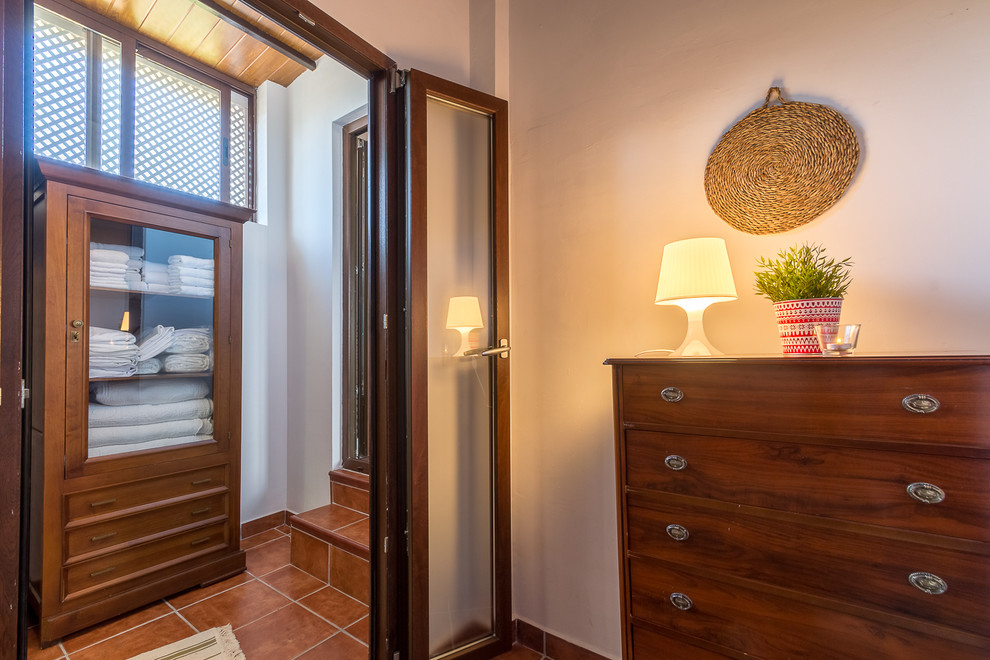 Esempio di una piccola camera degli ospiti tradizionale con pareti bianche, pavimento in terracotta e pavimento marrone