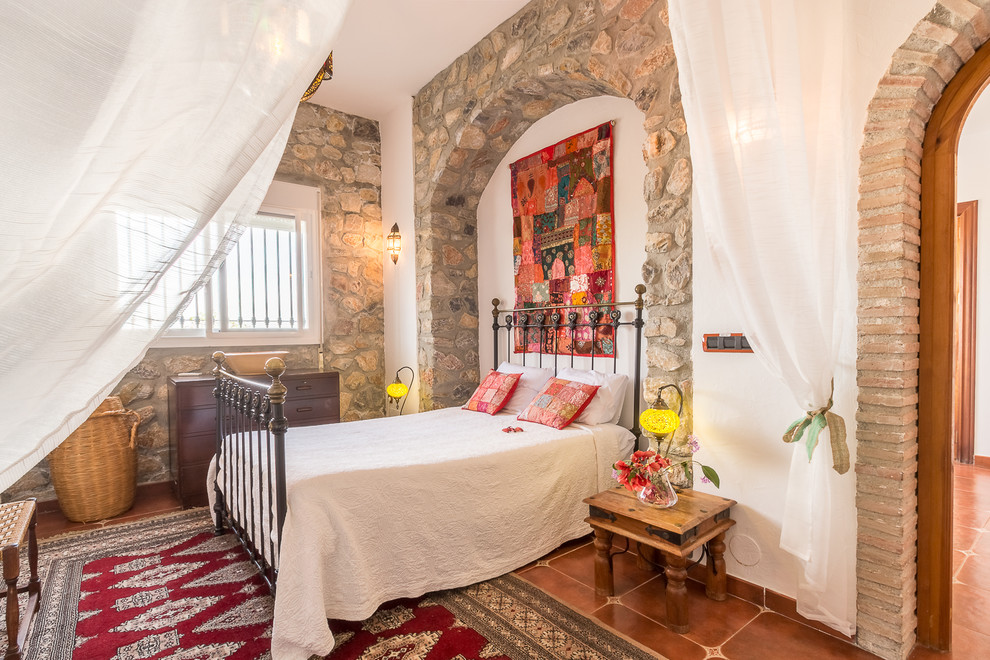 На фото: спальня в средиземноморском стиле с белыми стенами, коричневым полом и зонированием шторами